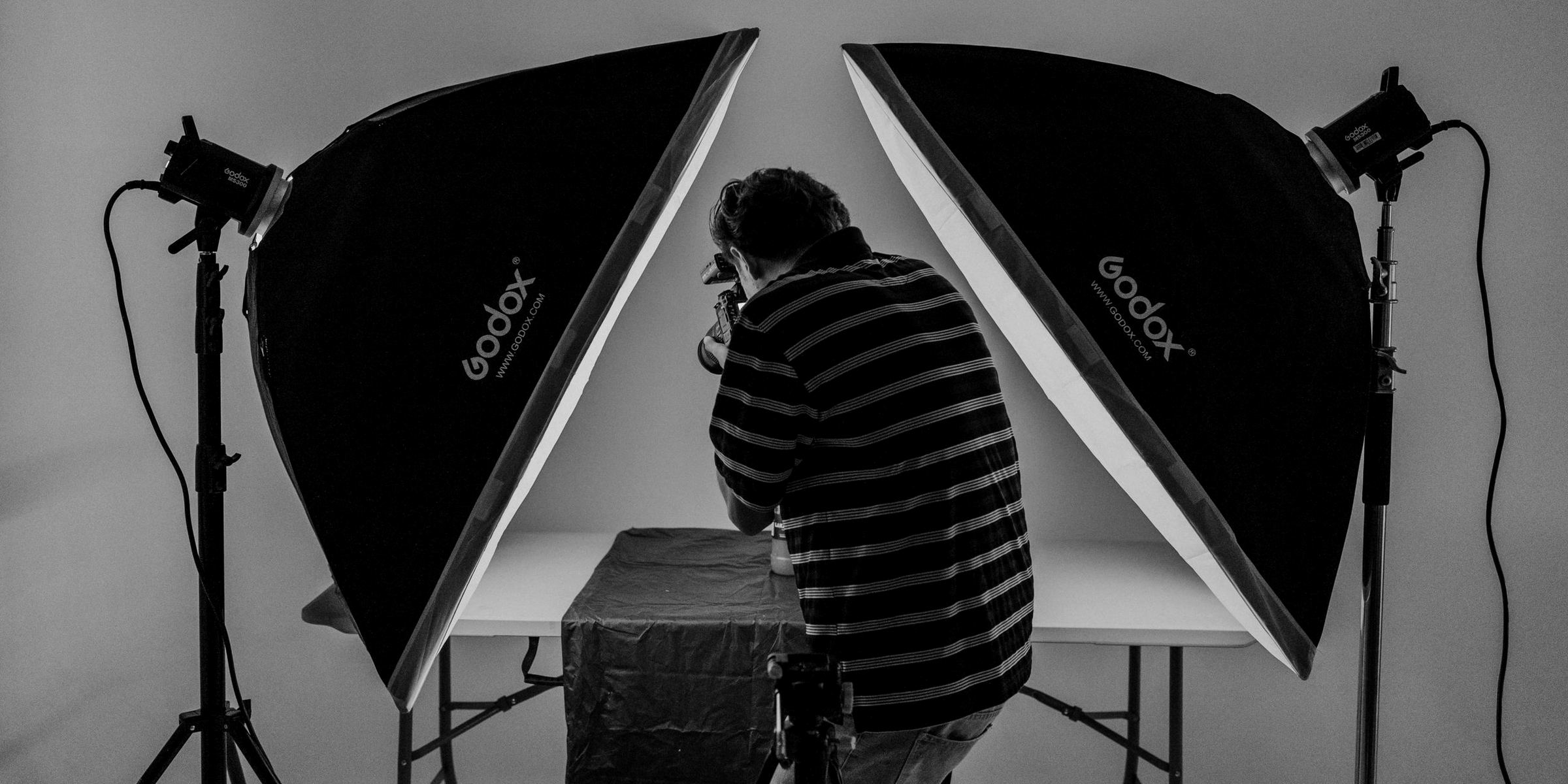 A photographer working between two softbox lights in a studio